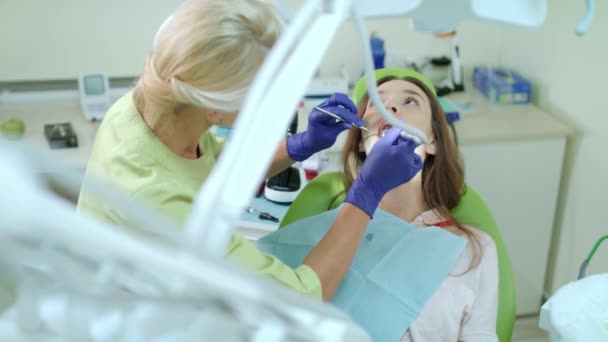 Οδοντίατρος γεώτρησης δόντι της γυναίκας. Ο γιατρός που εργάζεται με ασθενή σε οδοντιατρείο — Αρχείο Βίντεο