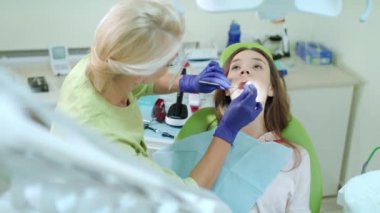 Stomatology doktor diş kliniğinde çalışıyor. Bayan hasta üzerinde inceleme bir dişçi