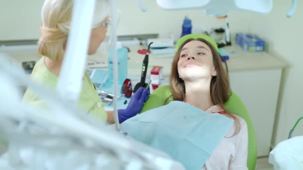 Женщина на регулярном стоматологическом осмотре в кабинете дантиста. Счастливая девушка в стоматологическом кресле — стоковое видео