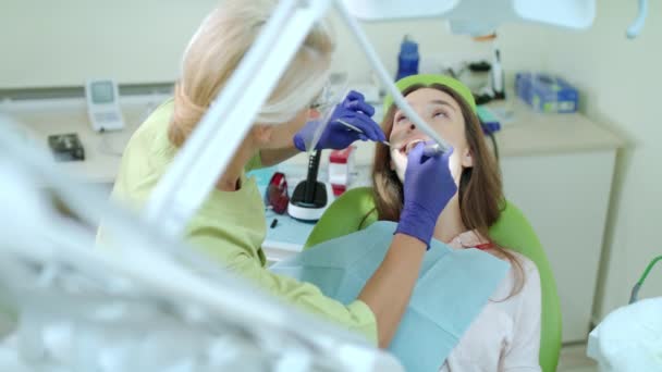 Zahnarzt bohrt kranken Zahn einer Patientin. Stomatologe mit Zahnbohrer — Stockvideo