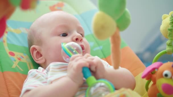 Bebé jugando sonajero bebé. Dulce cara de bebé con juguete. Adorable niño con sonajero — Vídeo de stock