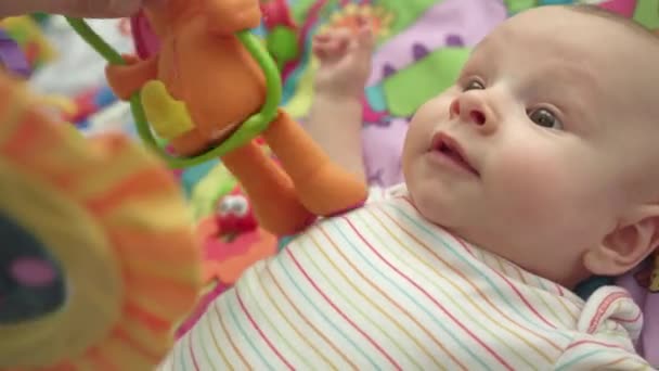 Sweet baby hrací hračka. Detailní záběr roztomilé dítě chlapce ležící na barevné mat — Stock video