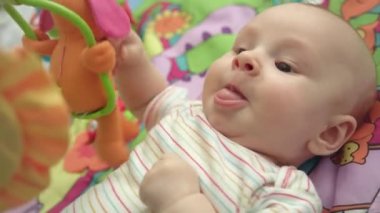 Bebek gösteren dilini kapatın. Şirin bebek oyuncakları ile oynarken portresi. Yeni doğan bebek duygu