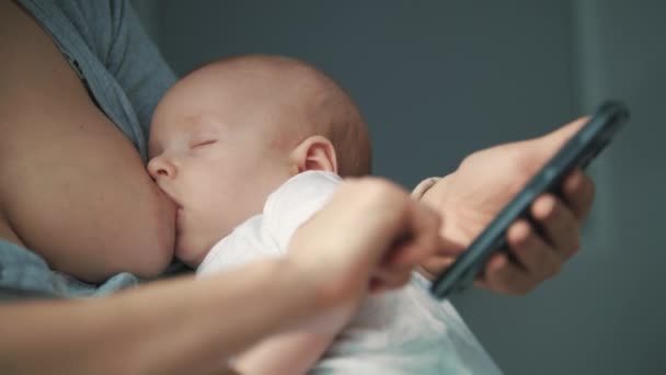 Κοντινό πλάνο γυναίκα που χρησιμοποιούν κινητό τηλέφωνο ενώ στήθος-ταΐζοντας το νεογέννητο μωρό — Αρχείο Βίντεο