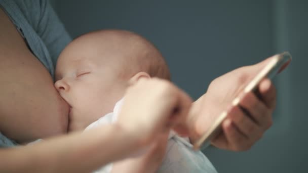 Breastfeeding mother using mobile phone. Breast feeding mom work on smartphone — Stock Video