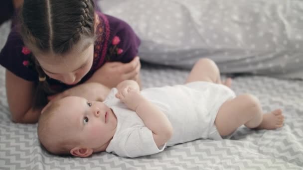 Girl kissing newborn baby lying on back. SIster love concept — Stock Video