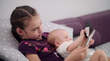 Kardeşiyle kitap okuma ufaklık. Yeni doğan bebek kardeş kucaklamak. Birlikte kitap okuma çocuk. Güzel kız erkek bebek tutan. Bebek eğitim kavramı