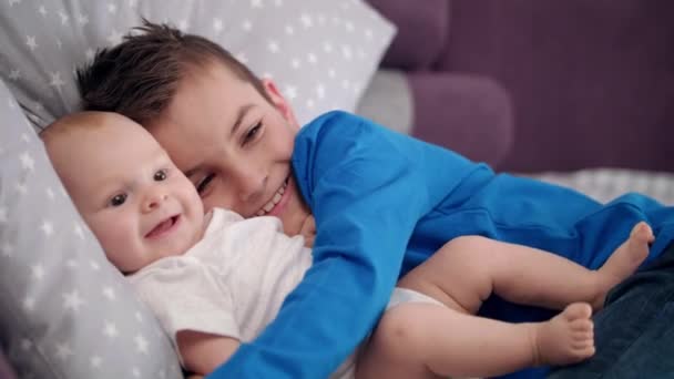 Porträt eines Jungen, der Säugling umarmt. glückliche Geschwister mit Baby. glückliche Brüder — Stockvideo