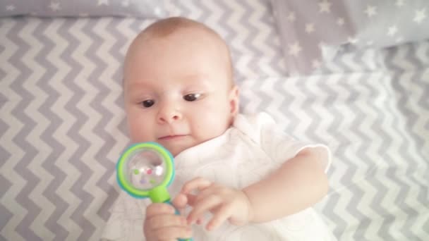 Portrait of cute baby boy playing toy. Cute child playing with rattle on bed — Stock Video