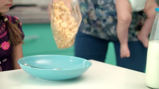 Материнские руки наливают хлопья кукурузы в голубую миску. Подготовка завтрака для ребенка — стоковое видео