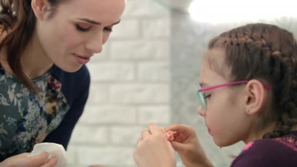Mamá limpia la cara hija. Chica comiendo cítricos con mamá. Comida saludable por la mañana — Vídeos de Stock