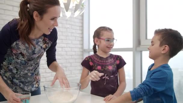 Familia de cocina divertirse en la cocina. Mujer cocinando pastel con niños — Vídeos de Stock