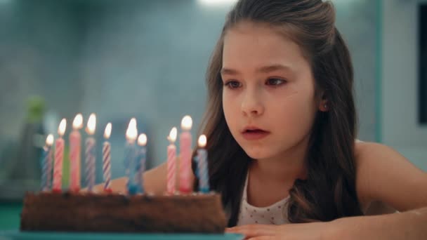 Porträt eines Mädchens, das Kerzen in Zeitlupe pustet. Kinderwunsch zum Geburtstag — Stockvideo