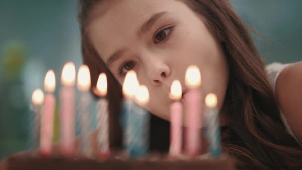 Chica bonita soplando llama de vela en pastel de cumpleaños en cámara lenta. Feliz cumpleaños. — Vídeo de stock