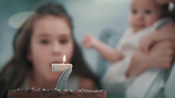Flicka blåser ljus på födelsedagstårtan på familjefest. Barn födelsedagen — Stockvideo