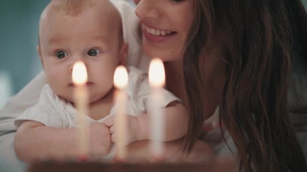 Máma s baby foukání narozeninovou svíčku. Žena s dítětem foukání svíčky na dort — Stock video