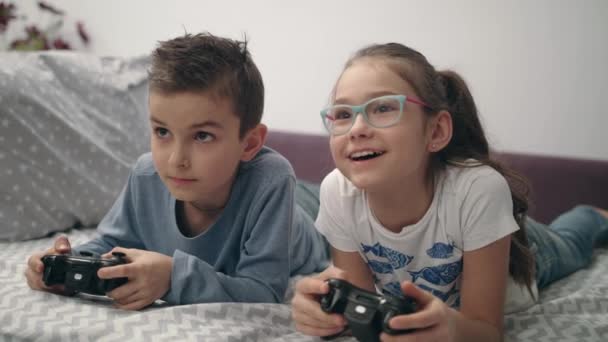 Niños felices jugando videojuegos con joystick en casa. Amigos jugar consola de juegos — Vídeo de stock