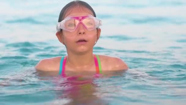 Ребенок в водолазной маске собирает воздух во рту и ныряет в воду — стоковое видео