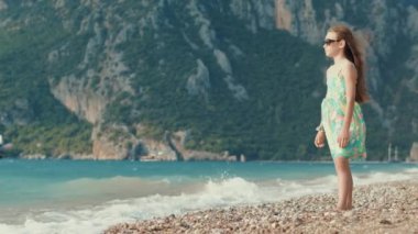 Genç kız karşı dağlar deniz plaj üzerinde düşünme. Çocuk sahilde rahatlatıcı