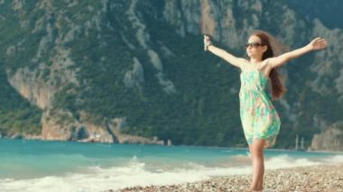 Güzel kız deniz plaj tatil keyfini çıkarın. Çocuk dağlar karşı silah yaymak