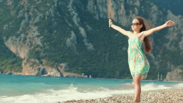 Mooi meisje geniet van vakantie aan zee strand. Kind verspreid wapens aan tegen bergen — Stockvideo