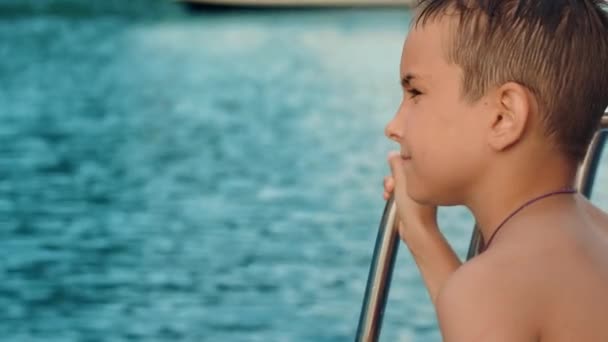 Child looking far into sea from yacht during cruise. Boy thinking before jumping — Stock Video