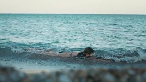 若い女の子がビーチで海にクロールします。ティーンエイ ジャーの女の子が海の休暇でリラックスします。 — ストック動画
