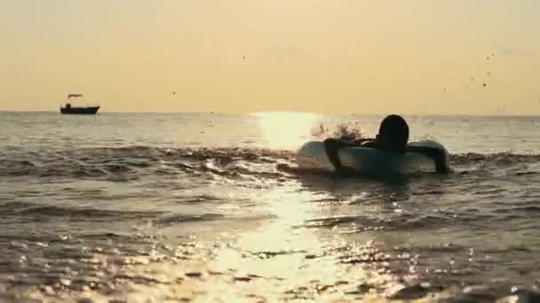 Boy swimming in sea on rubber ring and hitting water with feet — Stock Video