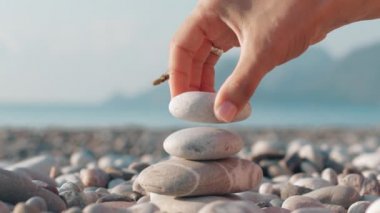Deniz plaj taş kule yapma ver. Sahilde dengeli çakıl yığını kapat. Kadın meditasyon, yaz tatili için piramit taş yapma