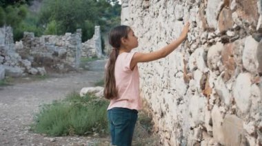 Genç kız eski duvar taşlarının dokunmadan. Eski duvarlara dokunmadan Thoughtfull kız