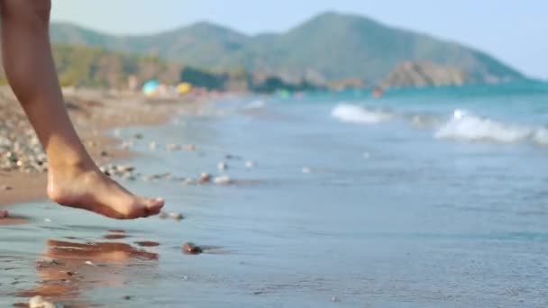 Mädchen, das Meerwasser zu Fuß berührt. Frauenfuß berührt Wasserwelle am Meeresstrand — Stockvideo