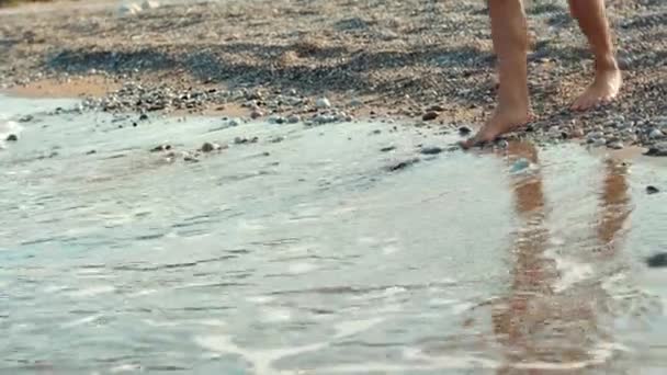 Niño tratando de bañarse en el mar frío. Persona tratar la temperatura del agua en el mar con el pie — Vídeos de Stock