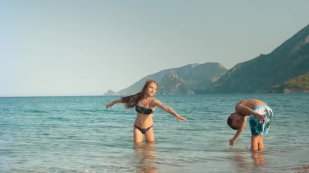 Les enfants font des mouvements de natation. Fille et garçon debout dans l'eau de mer — Video