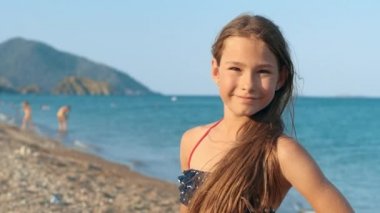 Deniz sahilinde gülümseyen kız portre. Mutlu çocuk vacations kameraya poz