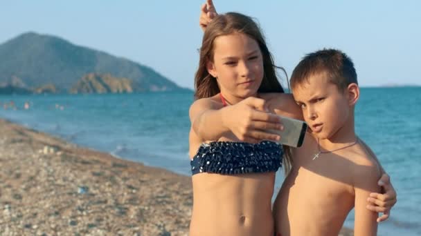 Alegre hermana y hermano haciendo selfie en el teléfono móvil en la playa del mar — Vídeos de Stock