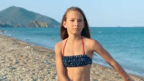Mladá dívka tančí veselý tanec na moře. Šťastné dítě baví na pláži — Stock video