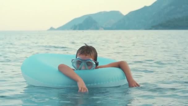 Niño durmiendo en un anillo de goma nadando en el mar. Niño relajándose en el mar — Vídeos de Stock