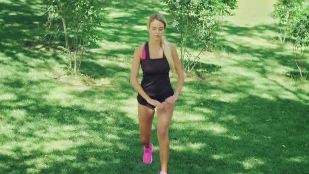 Strečink před montáží běží cvičení venkovní sportovní žena. Fit girl v podřepu — Stock video