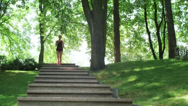 Fitness modell kör nedför trappor på utomhus träning i sommar park — Stockvideo