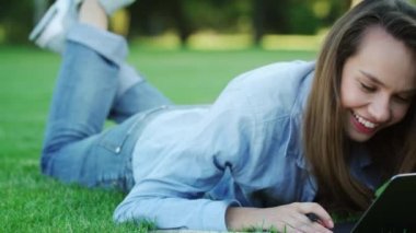 Mutlu kadın yaz Park yeşil çim üzerinde dizüstü bilgisayar kullanırken gülüyor