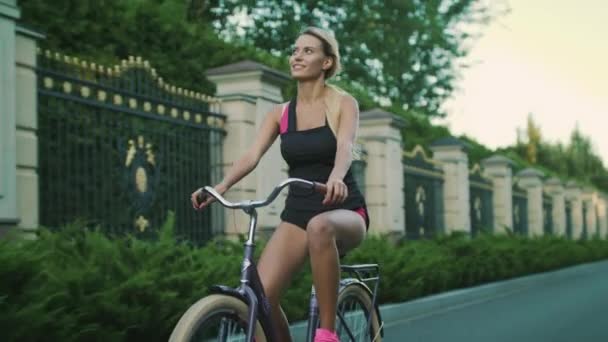 Mujer feliz bicicleta en el parque de la ciudad. Entrenamiento de chica en bicicleta en verano — Vídeos de Stock