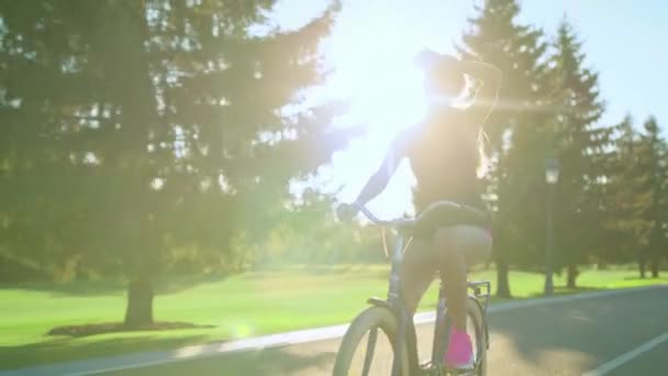 Уставшая велосипедистка вытирает пот с лица во время езды на велосипеде в летнем парке — стоковое видео