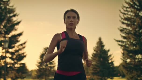 Uma jovem corredora a correr no parque ao pôr-do-sol. Fitness mulher correndo no parque — Vídeo de Stock