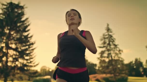 Deportiva mujer entrenamiento correr limpiando el sudor de la frente en el parque de verano por la noche — Vídeo de stock