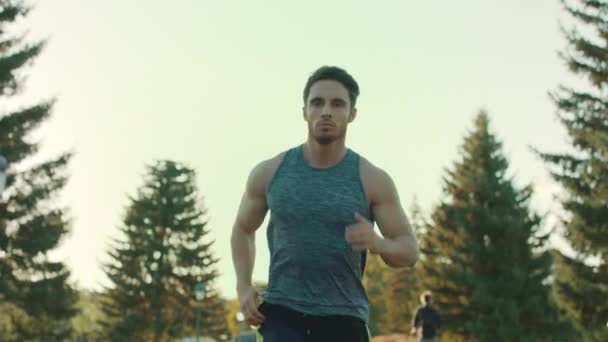 Молодой человек бежит в парке. Спортивный спортсмен бегает на улице. Уставший бегун — стоковое видео