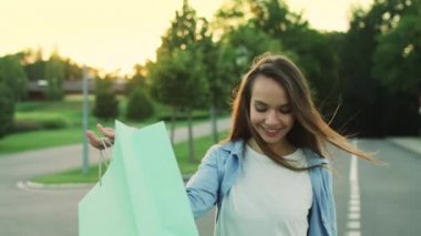 Gülümseyen kadın ile alışveriş çantası şehir park Caddesi'nde yürürken. Mutlu kadın