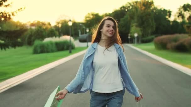 Šťastná žena s nákupem v pytli, chůze v městském parku. Šťastná dívka — Stock video