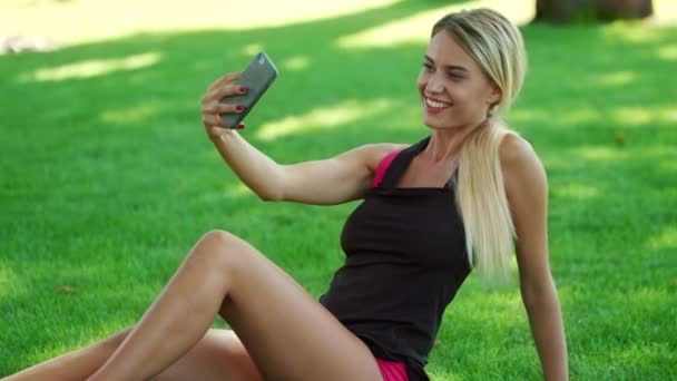 Blond kvinna tar selfie foto på mobiltelefon i sommaren park — Stockvideo