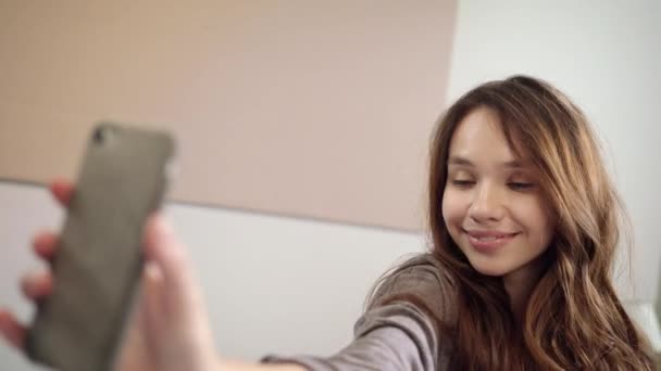 Ung kvinna tar selfie foto på mobiltelefon i sovrum — Stockvideo