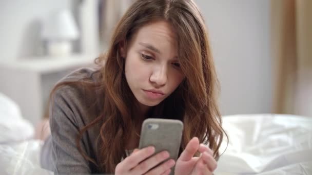 Geschokt vrouw VIDEONIEUWS online op mobiele telefoon kijken op ochtend — Stockvideo